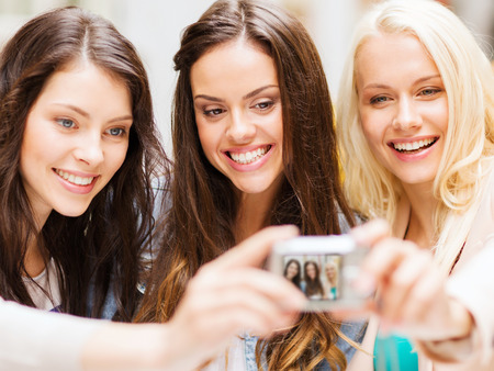 holidays and tourism concept - beautiful girls taking picture in cafe in city