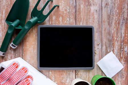 gardening technology and planting concept  close up of tablet pc computer blank screen seeds and garden tools on tableの写真素材