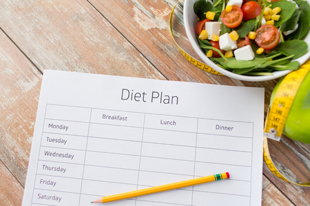 healthy eating dieting slimming and weigh loss concept close up of diet plan paper green apple measuring tape and salad healthy eating dieting slimming and weigh loss concept close up of diet plan paper green apple measuring tape and salad