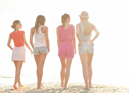 summer vacation, holidays, travel, friendship and people concept - group of young women walking on beachの写真素材