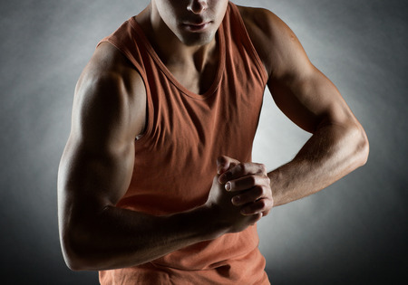 sport, bodybuilding, strength and people concept - young man showing biceps over black backgroundの写真素材