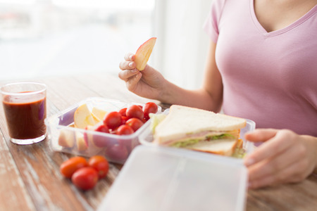 healthy eating, storage, dieting and people concept - close up of woman with food in plastic container at home kitchenの写真素材