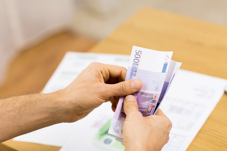 savings, finances, economy and home concept - close up of man hands counting money at home