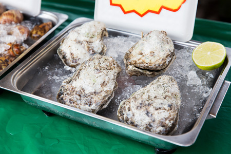 cooking, asian kitchen, sale and food concept - chilled oysters or seafood on ice at street marketの写真素材