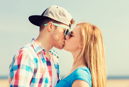 holidays, vacation and love concept - teenage couple kissing outdoors