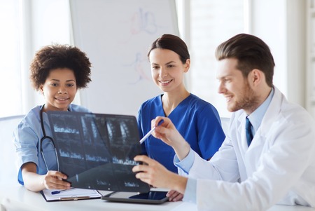 radiology, people and medicine concept - group of happy doctors looking to and discussing x-ray image at hospitalの写真素材