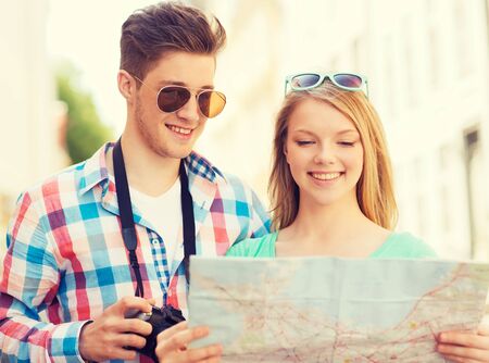 smiling couple with map and photo camera exploring cityの写真素材