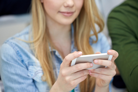 people, technology and internet concept - close up of teenage girl hands with smartphoneの写真素材