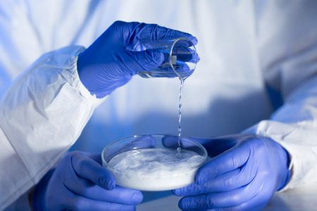 science, chemistry and people concept - close up of scientists hands with glass and chemical powder in petri dish making test or research at laboratoryの写真素材