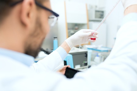 science, chemistry, biology, medicine and people concept - close up of male scientist with test tube and pipette making research in clinical laboratoryの写真素材