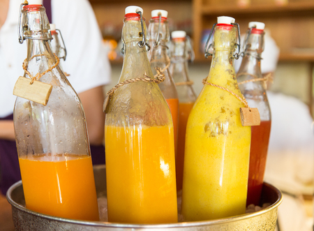 drinks, thirst, refreshment and sale concept - bottles of fruit or vegetable juice in ice bucket at marketの写真素材