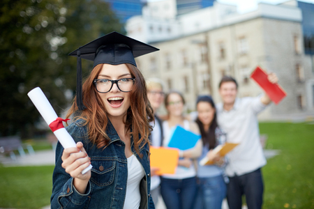group of smiling students in mortarboard with diploma and school foldersの写真素材