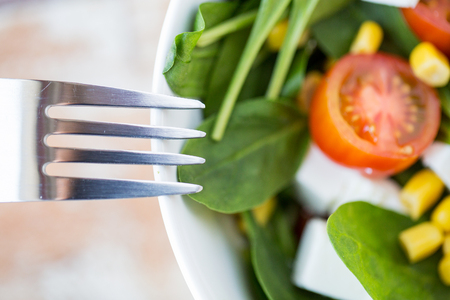healthy eating, dieting, vegetarian kitchen and cooking concept - close up of vegetable salad bowl and fork at homeの写真素材
