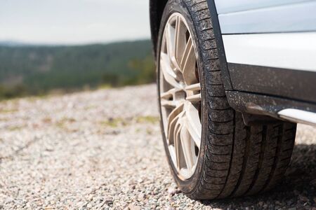 transport, driving and motor vehicle concept - close up of dirty car wheel on cliff