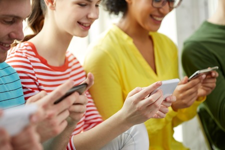education, people and technology concept - close up of smiling students with smartphones at schoolの写真素材