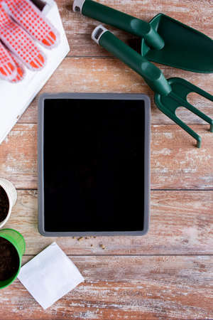 gardening, technology and planting concept - close up of tablet pc computer blank screen, seeds and garden tools on tableの写真素材