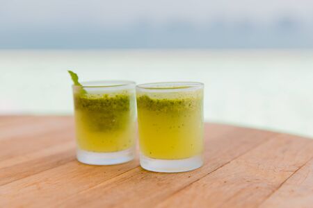 travel, tourism, drinks and food concept - glasses of fresh juice or cocktail on table at beach