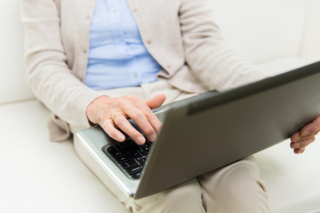 technology, age and people concept - close up of senior woman with laptop computer at home