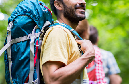 adventure, travel, tourism, hike and people concept - close up of friends walking with backpacks in woodsの写真素材
