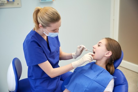 people, medicine, stomatology and health care concept - happy female dentist with mirror checking...