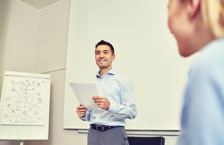 business, people and planning concept - smiling businessman and woman with papers meeting on presentation in office