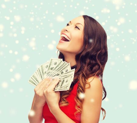 christmas, x-mas, sale, banking concept - smiling woman in red dress with us dollar moneyの写真素材
