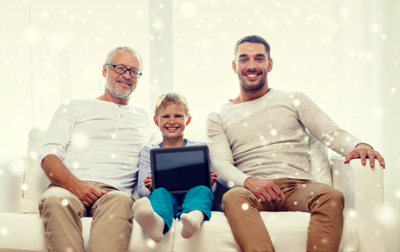 family, generation, technology and people concept - smiling father, son and grandfather sitting on couch with tablet pc computer at homeの写真素材