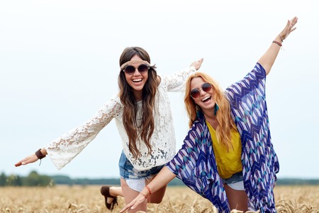 nature, summer, youth culture, friendship and people concept - smiling young hippie women having fun on cereal fieldの写真素材