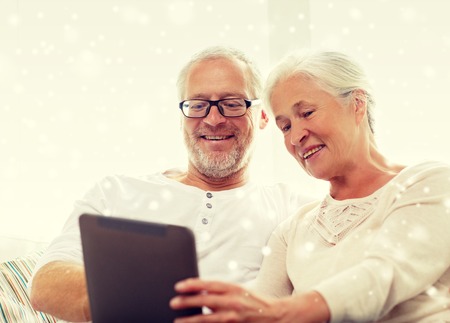 family, technology, age and people concept - happy senior couple with tablet pc computer at homeの写真素材