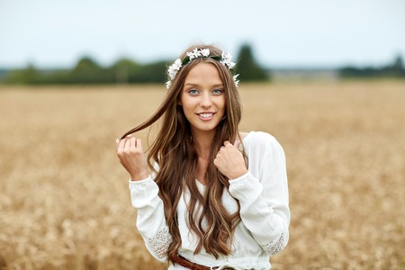nature, summer, youth culture and people concept - smiling young hippie woman wearing flower wreath on cereal fieldの写真素材