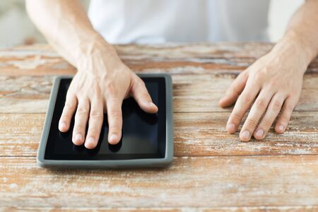 business, people and technology concept - close up of male hands with tablet pc computer on table