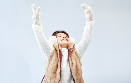 winter, people, happiness concept - happy little girl wearing earmuffs