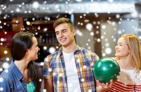 people, leisure, sport, friendship and entertainment concept - happy friends in bowling club at winter seasonの写真素材