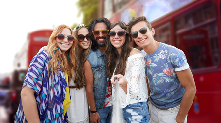 summer vacation, travel, tourism, technology and people concept - smiling young hippie friends...