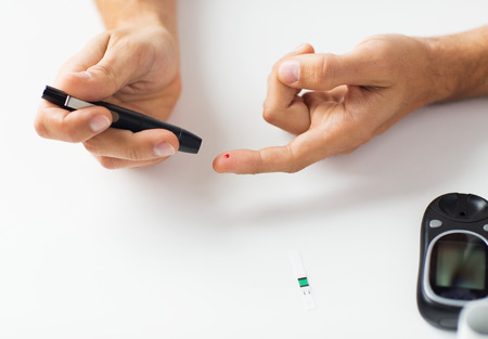 medicine, diabetes, glycemia, health care and people concept - close up of man checking blood sugar...