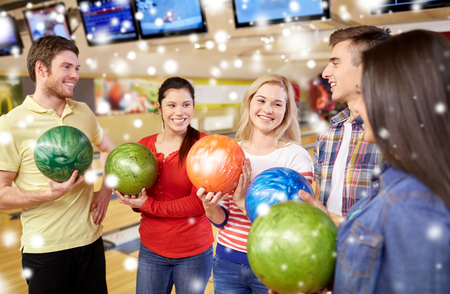 people, leisure, sport, friendship and entertainment concept - happy friends in bowling club at winter seasonの写真素材