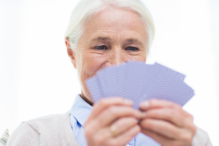 age, game, gamble, poker and people concept - close up of happy smiling senior woman playing cards at homeの写真素材