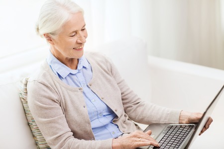 technology, age and people concept - happy senior woman with laptop computer at home