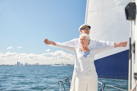 sailing, age, tourism, travel and people concept - happy senior couple enjoying freedom on sail boat or yacht deck floating in seaの写真素材