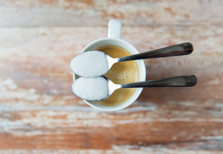 junk-food, diabetes and unhealthy eating concept - close up of white sugar on teaspoon and coffee cupの写真素材