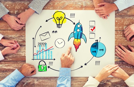 business, people, strategy and team work concept - close up of hands pointing finger to paper with scheme on table in officeの写真素材