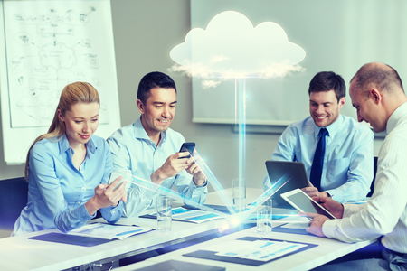 business, people, cloud computing and technology concept - smiling business team with smartphones, tablet pc computers working in office