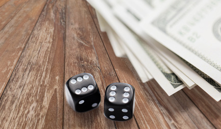 casino, gambling and fortune concept - close up of black dice and dollar cash money on wooden tableの写真素材