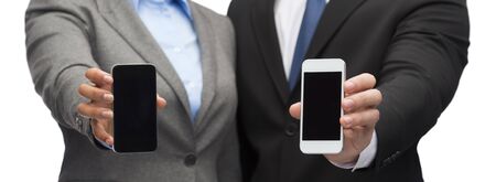 business, technology and internetconcept - businessman and businesswoman with blank black smartphone screensの写真素材