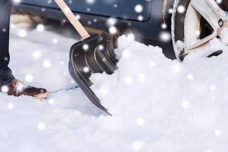 closeup of man digging snow with shovel near carの写真素材