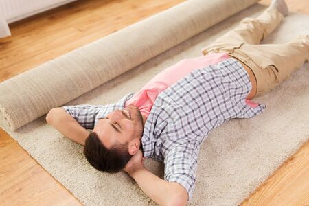 happy man lying carpet or rug on floor at homeの写真素材