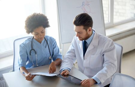 health care, people, technology and medicine concept - doctor and nurse with tablet pc computer and clipboard meeting and discussing something at hospitalの写真素材