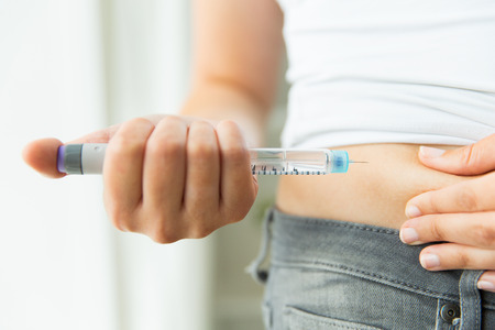 medicine, diabetes, glycemia, health care and people concept - close up of woman hands making injection with insulin pen or syringeの写真素材