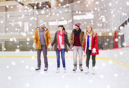 people, friendship, sport and leisure concept - happy friends on skating rinkの写真素材