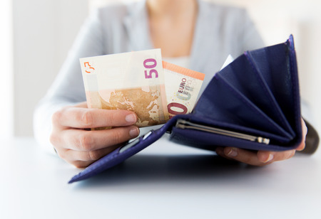 business, finance, saving, banking and people concept - close up of woman hands with wallet and euro moneyの写真素材